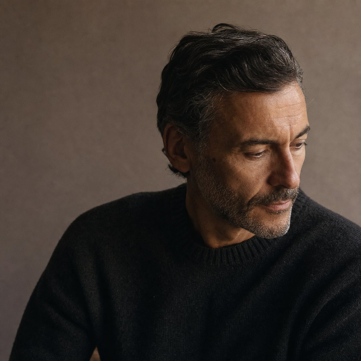 Portrait of a man in his forties in a charcoal knit, skin clear and well cared for